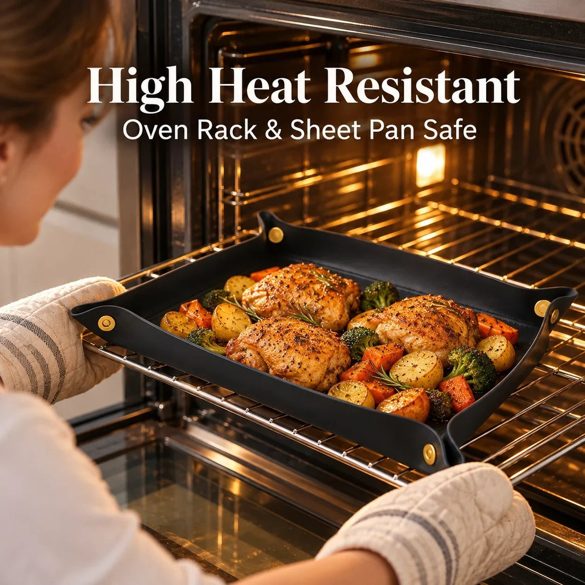 Black snap-corner silicone cooking mat holding baked chicken and vegetables inside an oven